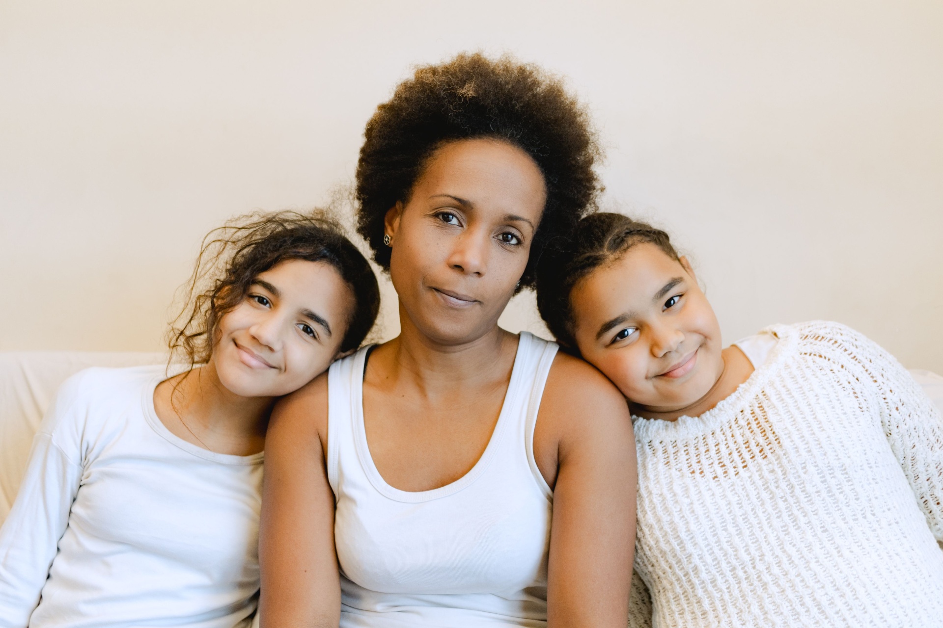 A mother with her two daughters sitting closely together on a couch